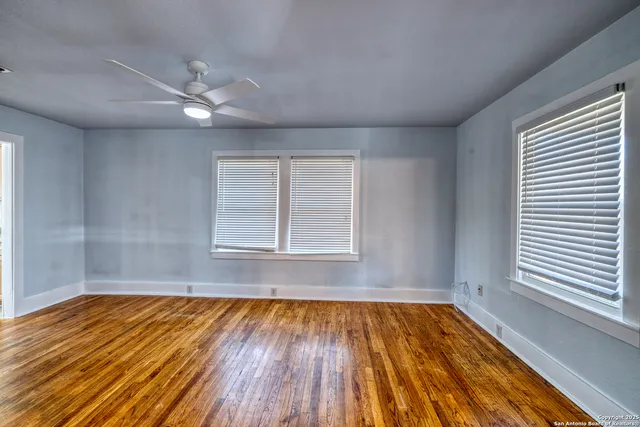an empty room with wooden floor and windows