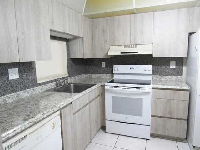 a kitchen with granite countertop a sink a stove and cabinets