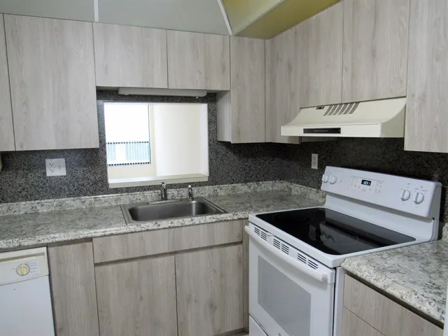 a kitchen with granite countertop a sink a stove and cabinets