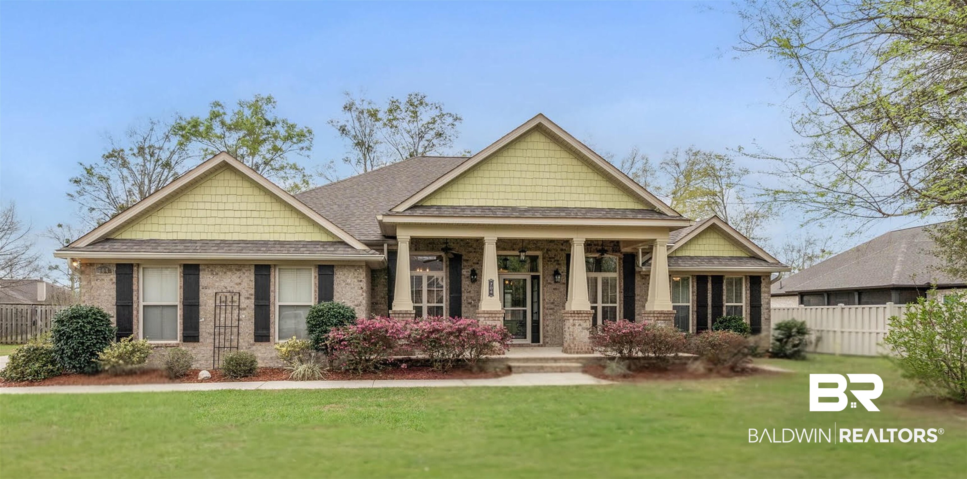 704 Edinburgh Avenue Foley, AL 36535 - Photo 1 of 32 Brick ranch-style residence featuring a welcoming covered front porch with substantial columns, shuttered windows, and a manicured lawn with established landscaping