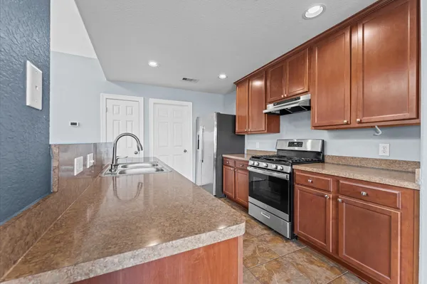 a kitchen with stainless steel appliances granite countertop a sink a stove and a refrigerator