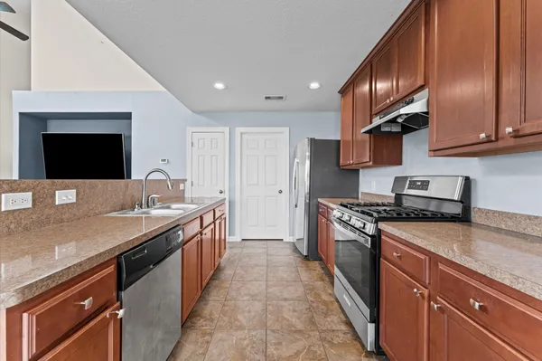 a kitchen with stainless steel appliances granite countertop a sink a stove and a wooden cabinets