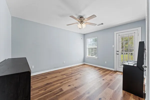 a view of an empty room with wooden floor and a window