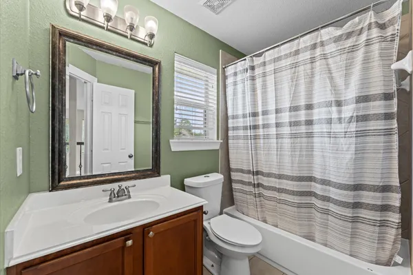 a bathroom with a sink a toilet a mirror and shower curtain