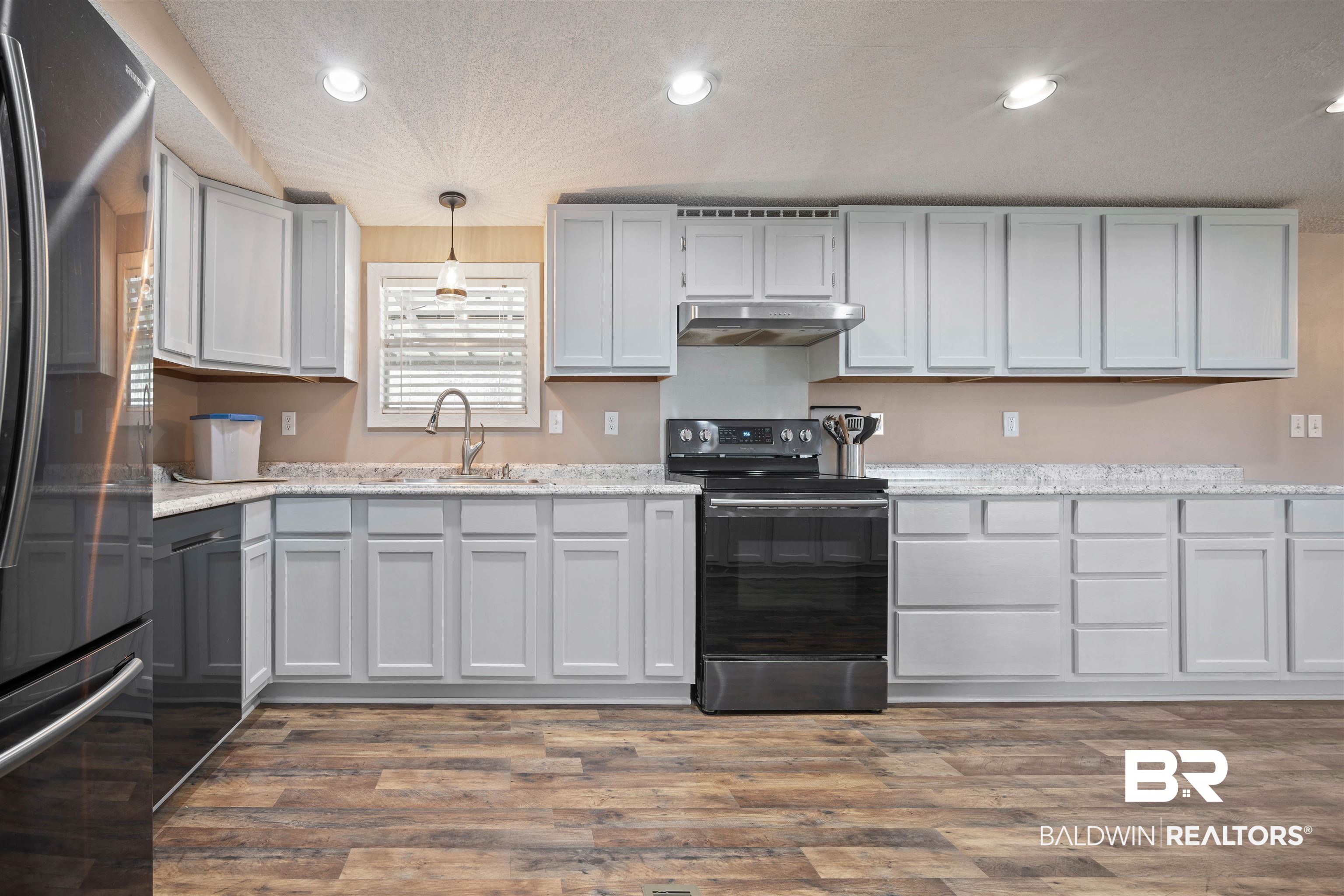 9011 Wilmer Georgetown Road Wilmer, AL 36587 - Photo 11 of 34 Kitchen featuring a sink, under cabinet range hood, black appliances, and dark wood-style flooring
