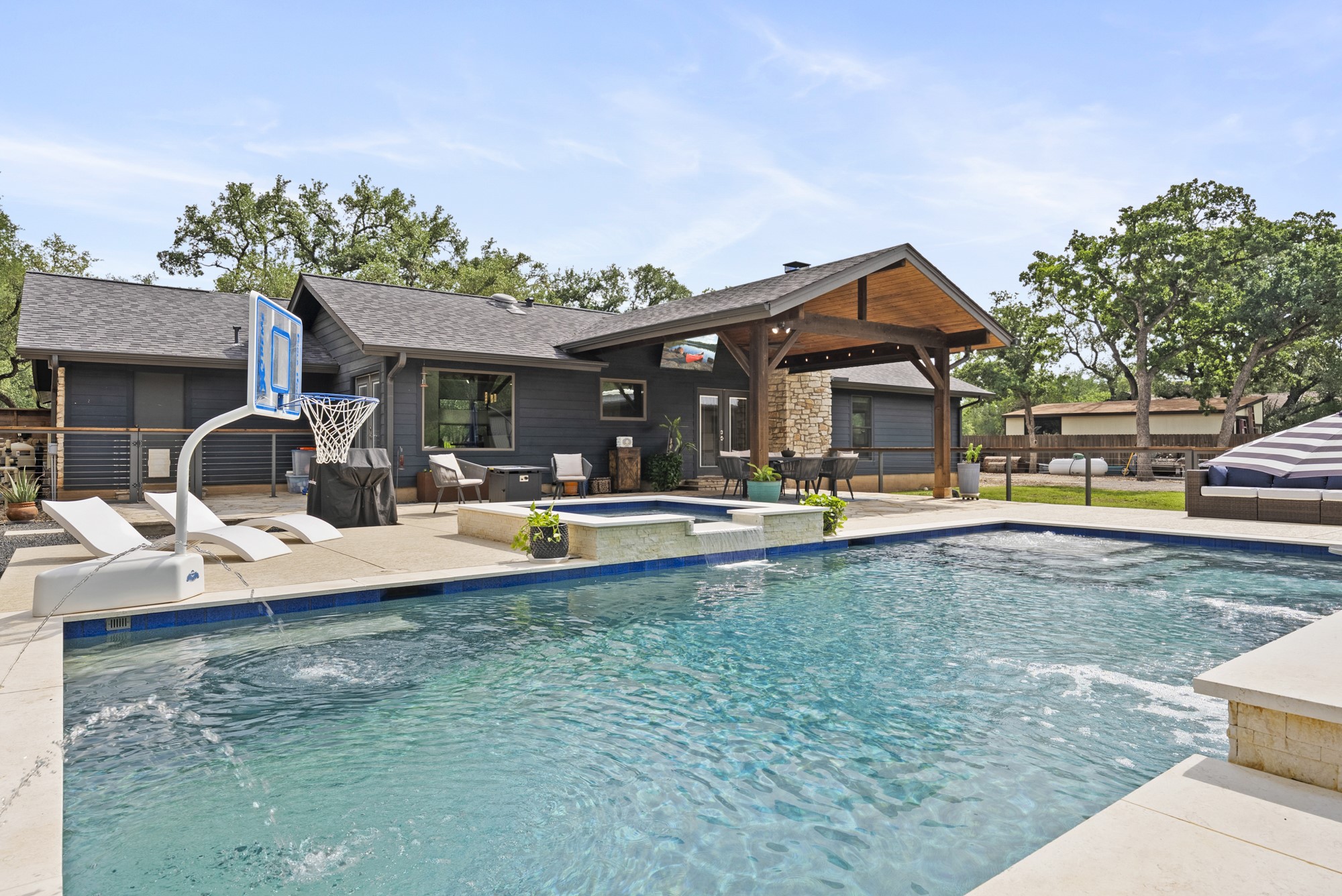 2802 Robin Road Manchaca, TX 78652 - Photo 21 of 40 Expansive backyard featuring a large swimming pool, integrated spa, and a covered patio with a vaulted wood ceiling and stone pillar accents