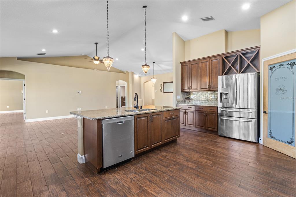 765 Sloans Ridge Road Groveland, FL 34736 - Photo 12 of 62 a kitchen with stainless steel appliances kitchen island granite countertop a stove a refrigerator a sink and a oven with wooden floor