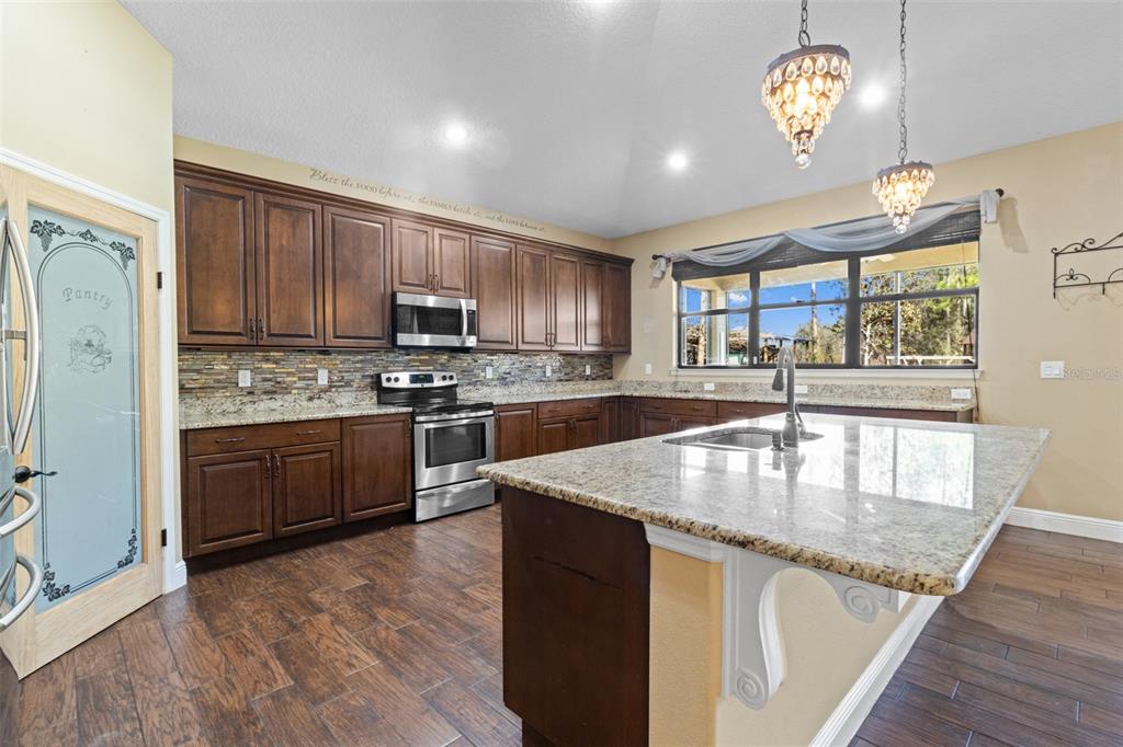 765 Sloans Ridge Road Groveland, FL 34736 - Photo 16 of 62 a kitchen with granite countertop stainless steel appliances a stove a sink a refrigerator cabinets and wooden floor