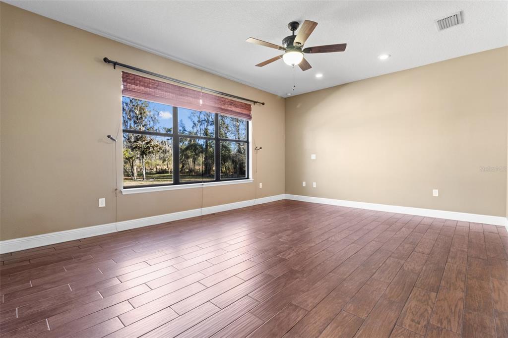 765 Sloans Ridge Road Groveland, FL 34736 - Photo 19 of 62 an empty room with wooden floor and windows