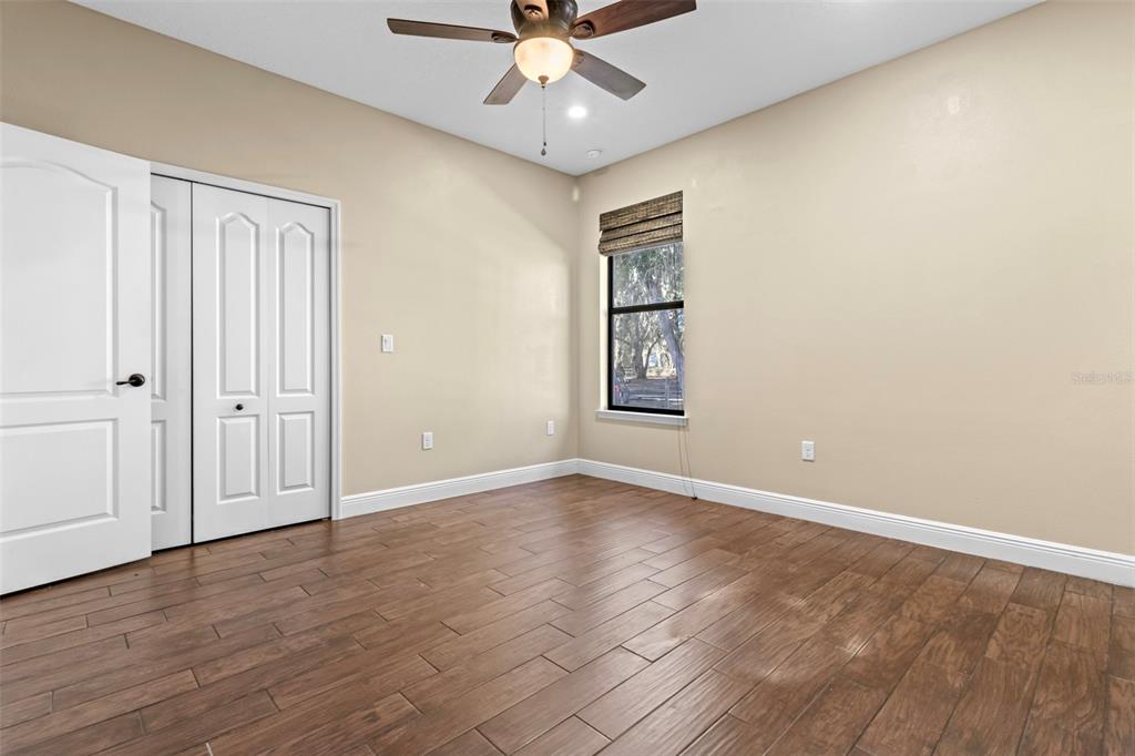 765 Sloans Ridge Road Groveland, FL 34736 - Photo 28 of 62 an empty room with wooden floor chandelier fan and windows