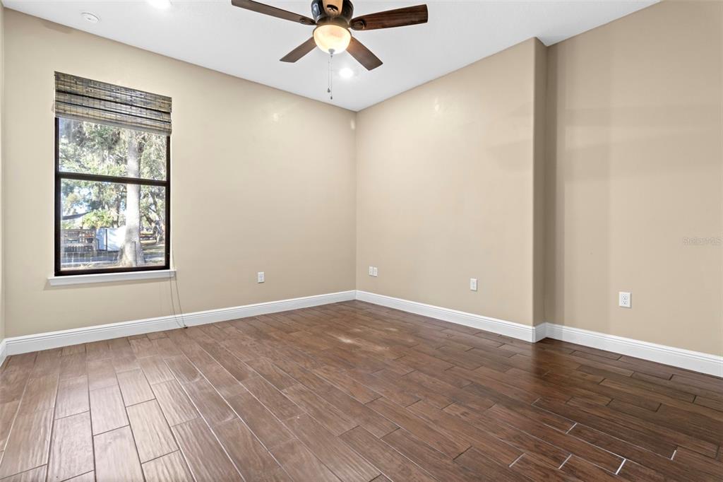 765 Sloans Ridge Road Groveland, FL 34736 - Photo 29 of 62 an empty room with wooden floor chandelier fan and windows