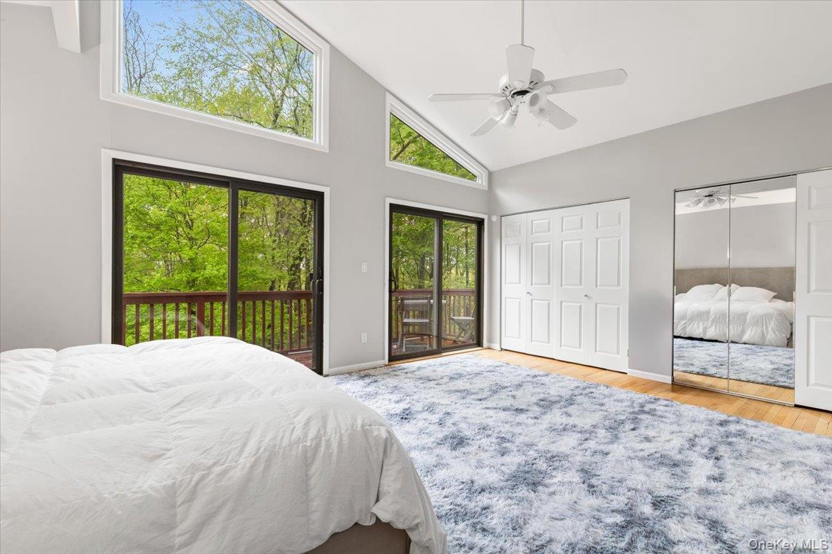 37 Talcott Road Rye Brook, NY 10573 - Photo 11 of 25 Vaulted ceiling room featuring multiple large windows, two sliding glass doors opening to a wood-railed deck, extensive closet storage, and wood flooring