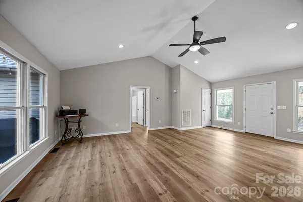 a view of an empty room with a window and wooden floor