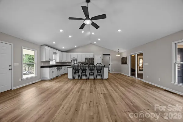 a living room with kitchen island stainless steel appliances furniture cabinets and a wooden floor