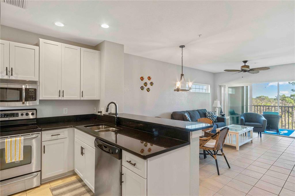 8409 Placida Road, Unit 405 Placida, FL 33946 - Photo 21 of 77 a kitchen with granite countertop a sink a stove cabinets and black appliances