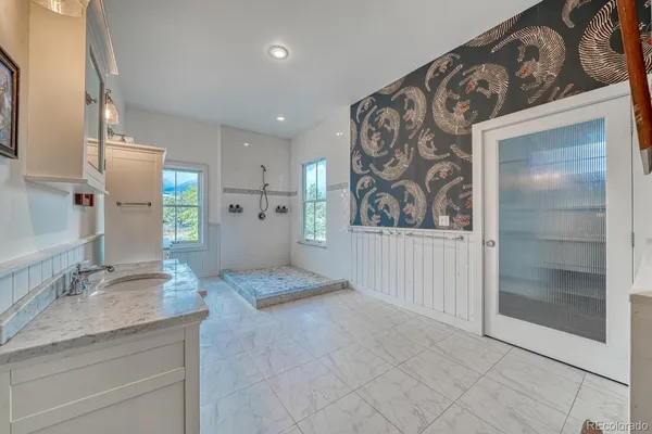 a spacious bathroom with a granite countertop sink a mirror a bathtub and shower