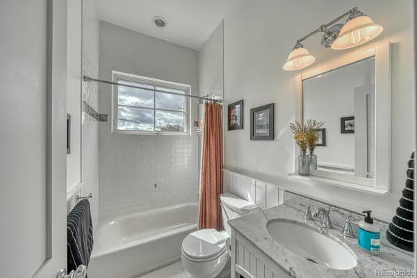 a bathroom with a granite countertop sink toilet mirror and bathtub