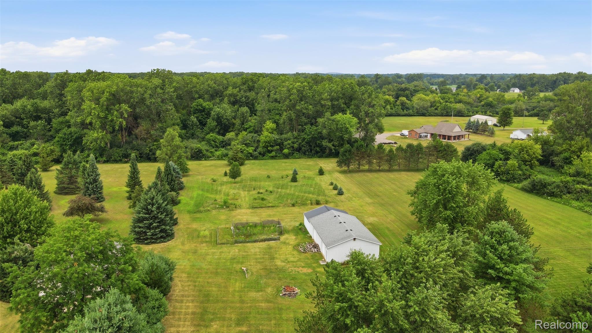 45738 Bemis Road Belleville, MI 48111 - Photo 47 of 52 Expansive green acreage with a large outbuilding, mature trees, and evergreen landscaping