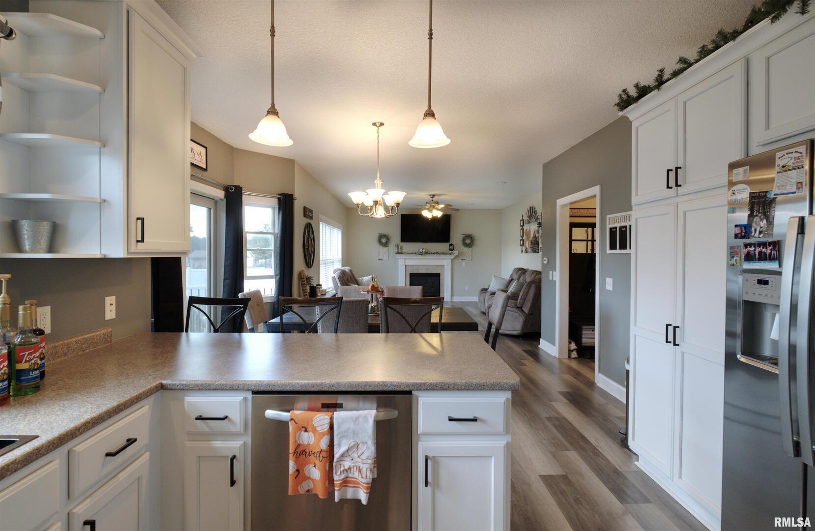 1917 11th Street Camanche, IA 52730 - Photo 6 of 40 a kitchen with stainless steel appliances kitchen island granite countertop a refrigerator a stove a sink dishwasher and white cabinets with wooden floor