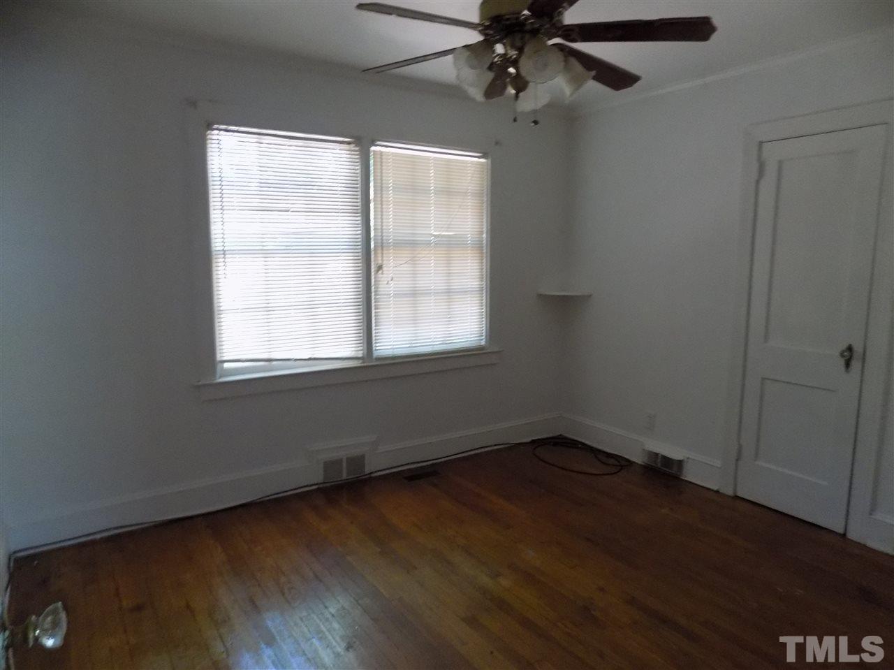 1114 Kent Road Raleigh, NC 27606 - Photo 4 of 10 an empty room with wooden floor fan and windows