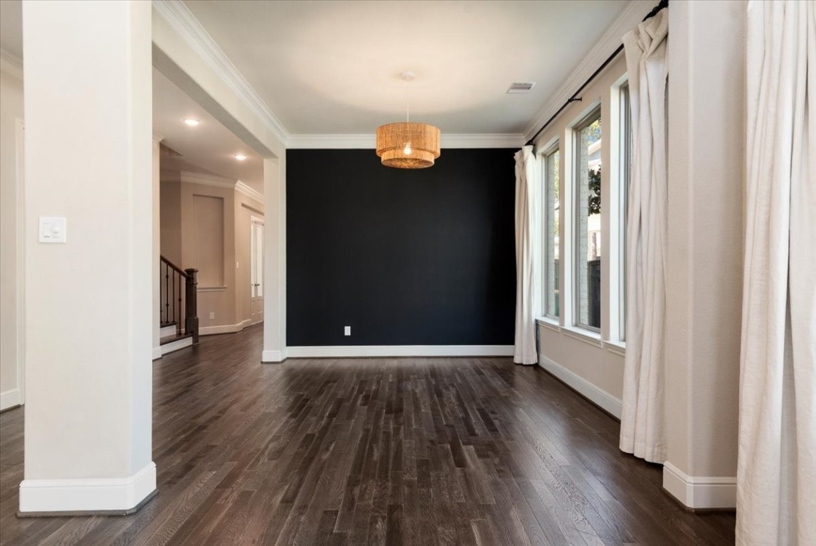 155 Rockwell Park Spring, TX 77389 - Photo 13 of 50 This room features an elegant open layout with dark wood flooring, a striking accent wall, and ample natural light from large windows with white curtains. A stylish pendant light adds a warm touch to the space.