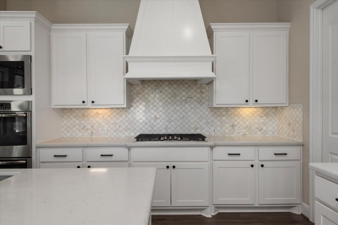 155 Rockwell Park Spring, TX 77389 - Photo 20 of 50 This modern kitchen features sleek white cabinetry, a stylish range hood, and a chic marble backsplash. It includes built-in stainless steel appliances and ample counter space, creating a bright and inviting cooking area.