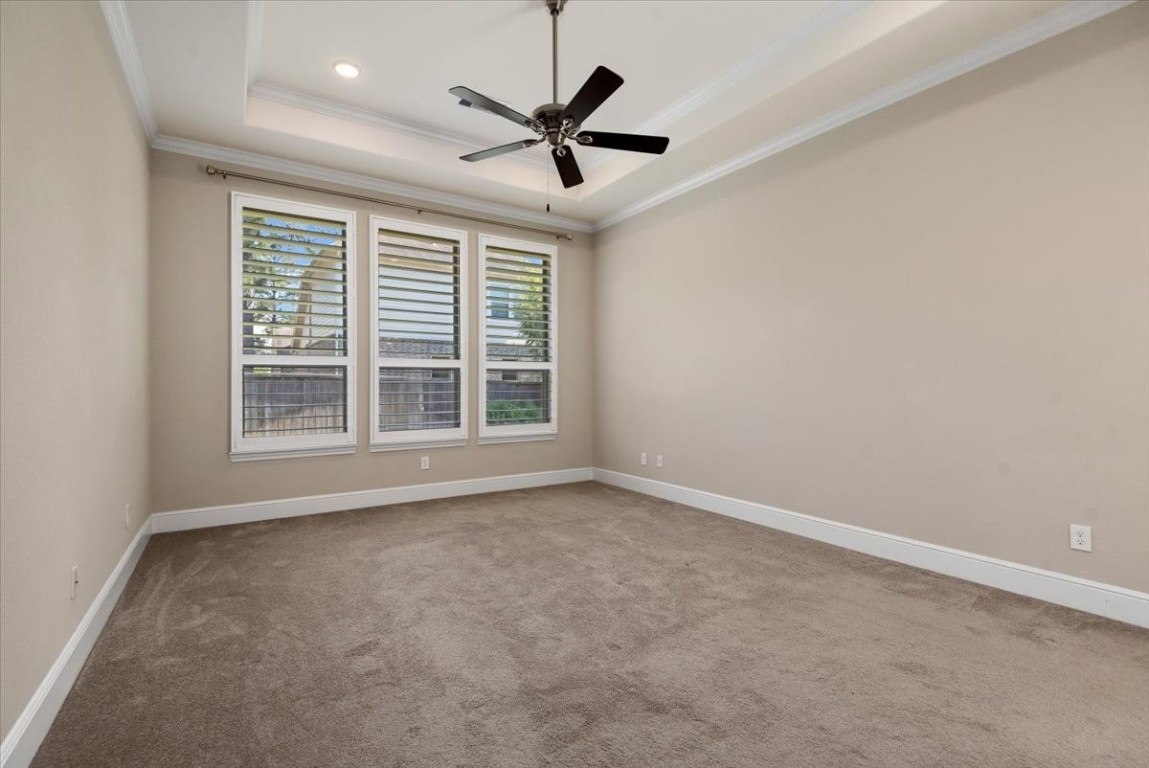 155 Rockwell Park Spring, TX 77389 - Photo 24 of 50 Experience tranquility in this spacious primary bedroom, featuring elegant tray ceilings, abundant natural light through large windows, and a stylish ceiling fan for ultimate comfort.