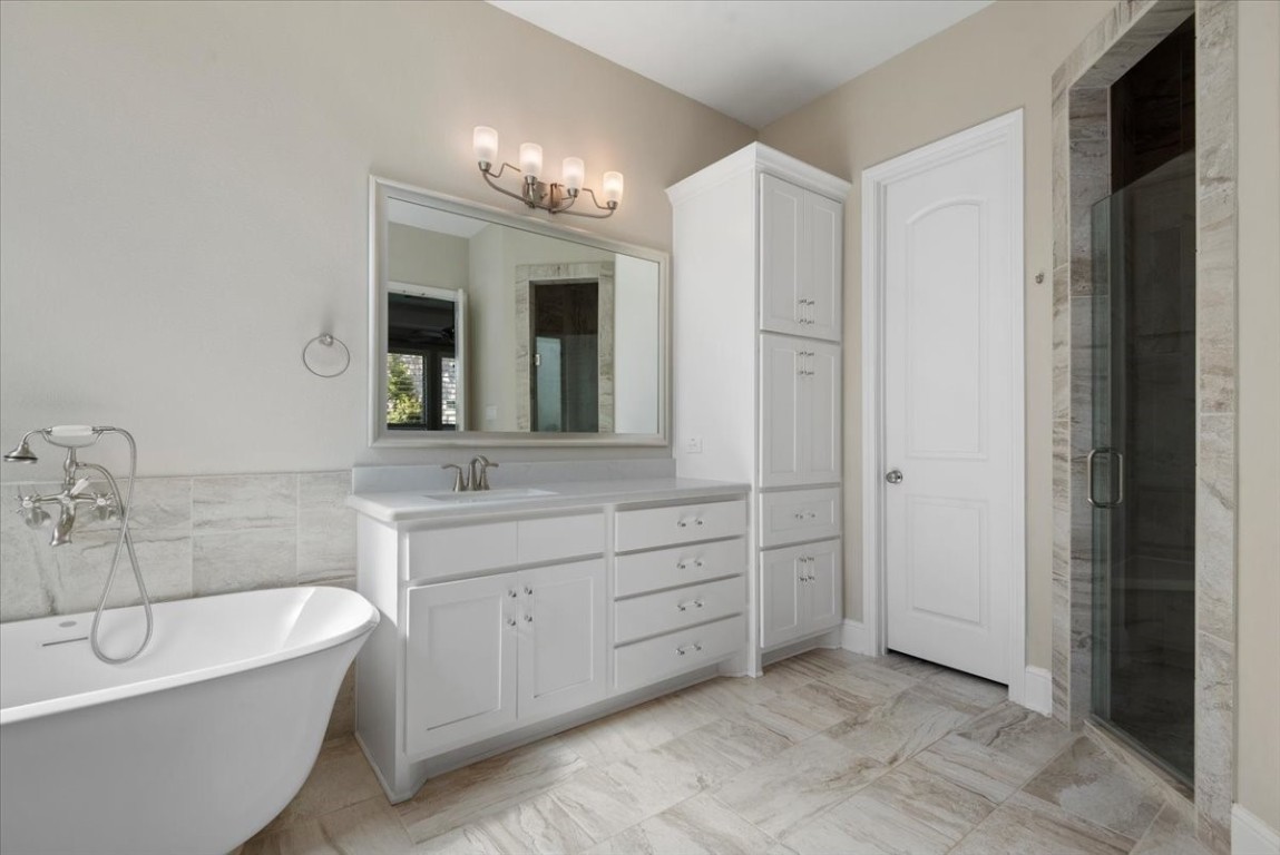 155 Rockwell Park Spring, TX 77389 - Photo 29 of 50 This bathroom features a sleek, modern design with a freestanding tub, spacious vanity with ample storage, elegant lighting, and a glass-enclosed shower. The neutral tones create a calming, spa-like atmosphere.