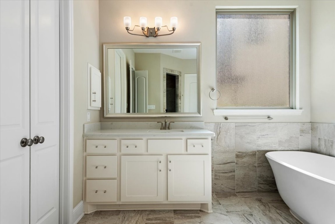 155 Rockwell Park Spring, TX 77389 - Photo 30 of 50 This bathroom features a modern design with a freestanding bathtub, large vanity with ample storage, elegant lighting, and a frosted window for privacy.