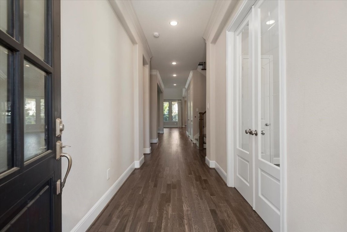 155 Rockwell Park Spring, TX 77389 - Photo 3 of 50 This photo shows a modern, well-lit hallway with hardwood floors and neutral walls. It features a glass-paneled door and leads to a space with abundant natural light, creating an inviting entrance to the home.