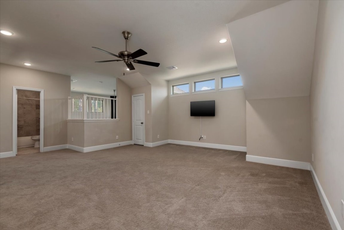 155 Rockwell Park Spring, TX 77389 - Photo 38 of 50 This spacious room features neutral walls and carpet, recessed lighting, a ceiling fan, and a wall-mounted TV. It includes a small window section for natural light and an attached bathroom, making it ideal for a versatile living space.