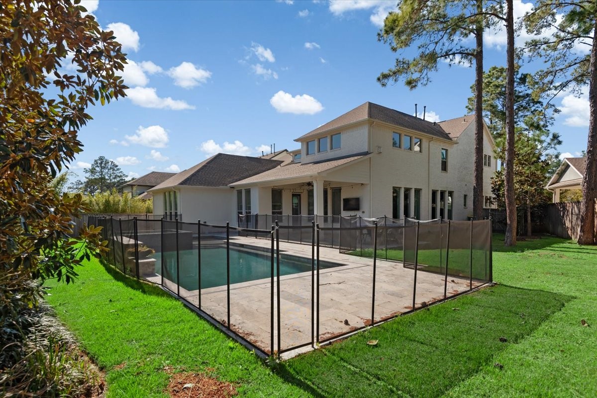 155 Rockwell Park Spring, TX 77389 - Photo 43 of 50 This photo showcases a spacious backyard featuring a fenced-in swimming pool, well-maintained lawn, and a modern two-story house with a covered patio. Ideal for family living and outdoor entertainment.