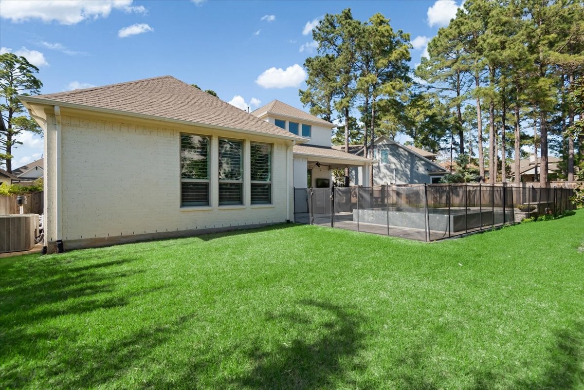 155 Rockwell Park Spring, TX 77389 - Photo 46 of 50 Spacious backyard featuring a well-maintained lawn and a fenced-in pool area, surrounded by mature trees providing natural shade and privacy.
