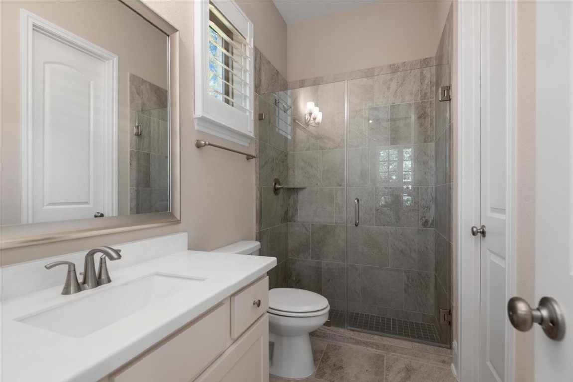 155 Rockwell Park Spring, TX 77389 - Photo 10 of 50 This modern en-suite bathroom features a sleek design with a glass-enclosed shower, elegant tile work, a large mirror, and a stylish vanity with ample storage.