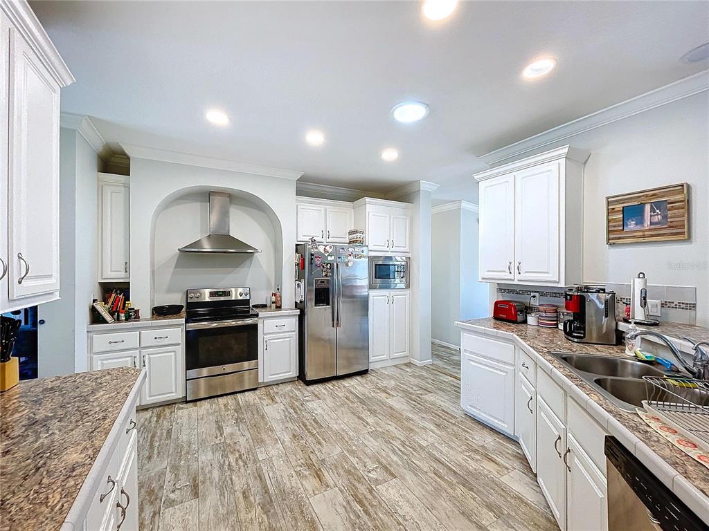 14890 County Road 757 Webster, FL 33597 - Photo 74 of 100 a kitchen with stainless steel appliances granite countertop a stove top oven a sink a refrigerator and white cabinets with wooden floor