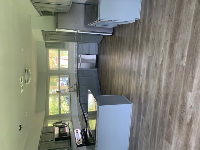 1501 North Burleson Street Kyle, TX 78640 - Photo 12 of 33 a large kitchen with stainless steel appliances wooden floors and a view of living room