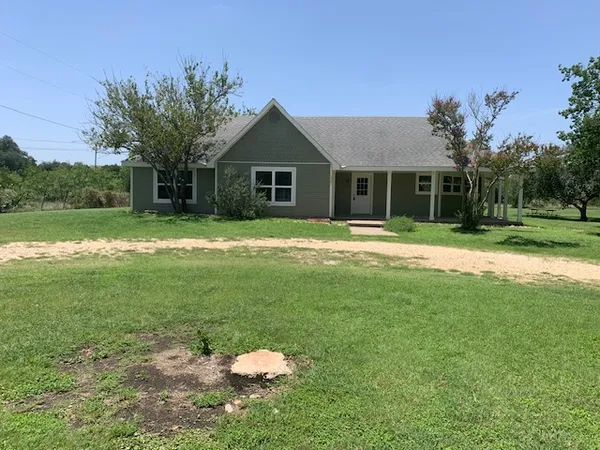 a front view of a house with a yard and trees