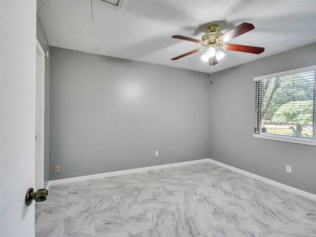 an empty room with windows and chandelier fan