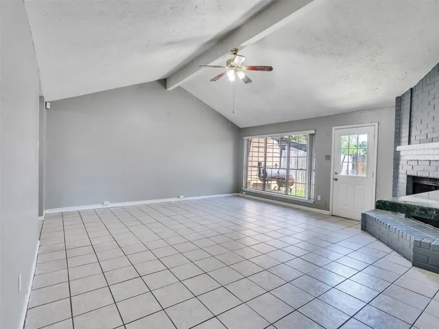 a view of an empty room with a fireplace and a window