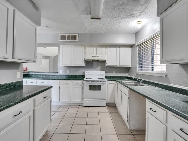 a kitchen with cabinets appliances a sink and a window