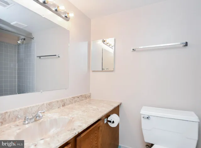 a bathroom with a granite countertop sink a toilet and mirror