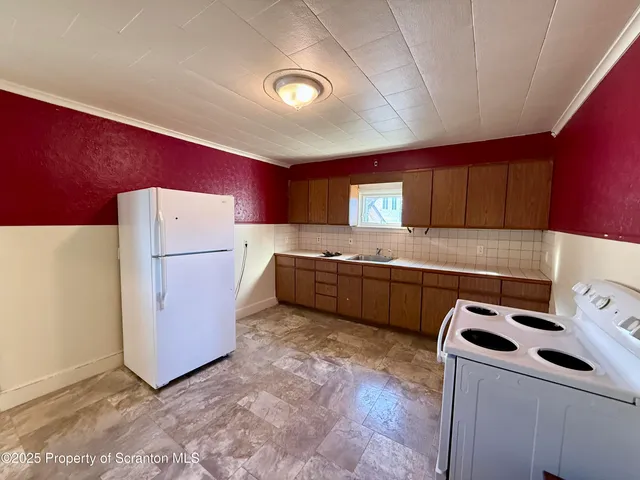 a kitchen with a refrigerator a stove top oven a sink and cabinets