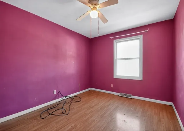 an empty room with a window and a fan