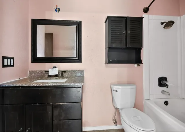 a bathroom with a granite countertop toilet sink and mirror