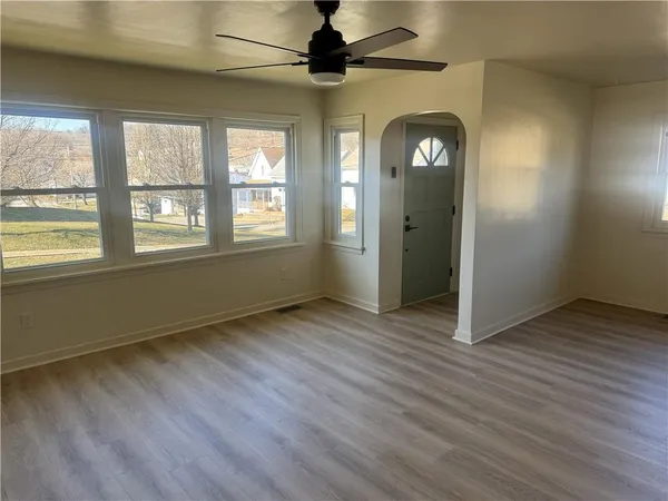 a view of an empty room with window and wooden floor