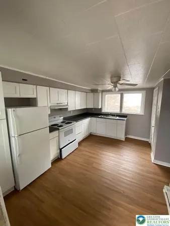 a kitchen with granite countertop a refrigerator and a stove top oven