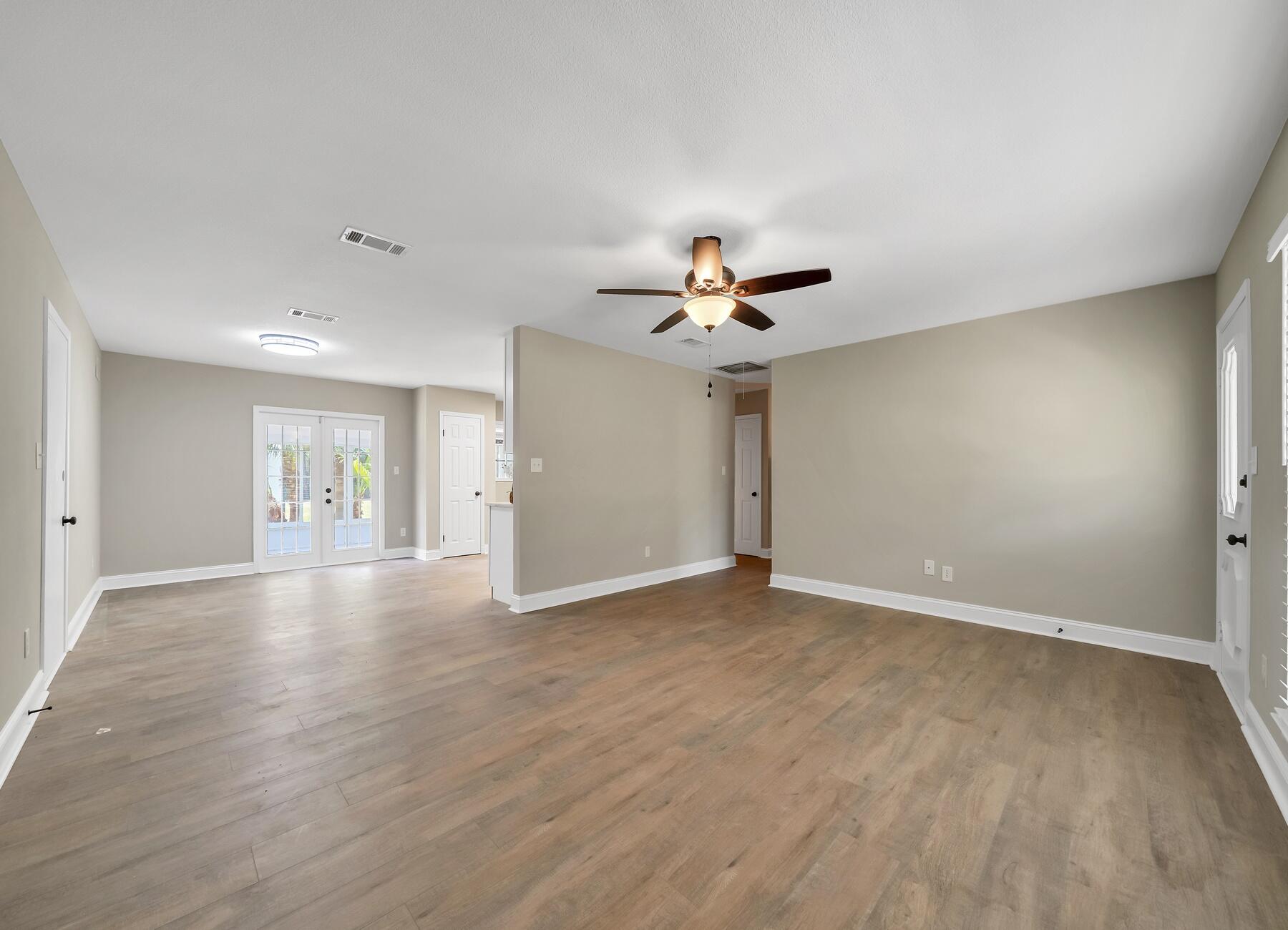 6935 Jasper Street Navarre, FL 32566 - Photo 11 of 45 a view of an empty room with wooden floor and a ceiling fan