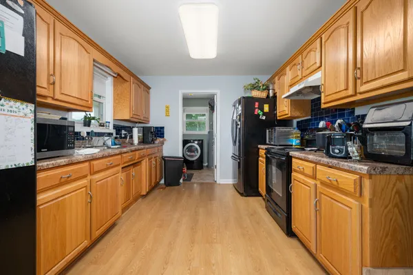 a kitchen with stainless steel appliances granite countertop a refrigerator a stove top oven a sink dishwasher and wooden cabinets with wooden floor