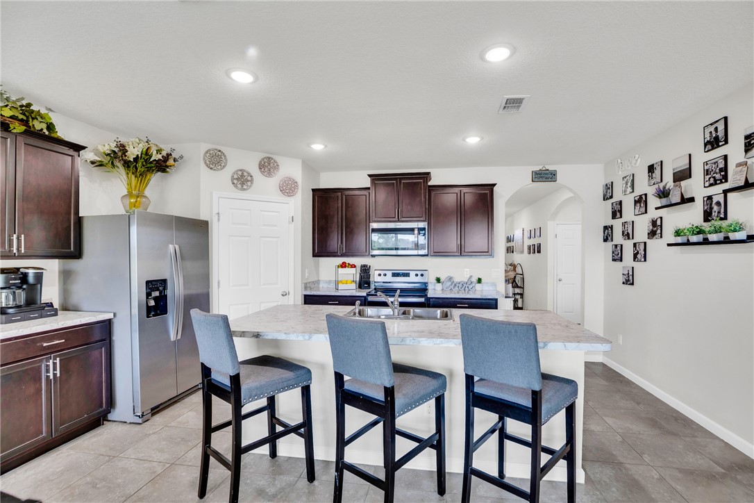 3453 Trinity Circle Fort Pierce, FL 34945 - Photo 5 of 36 a kitchen with stainless steel appliances a table and chairs in it