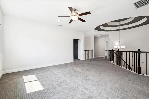 an empty room with chandelier fan and windows